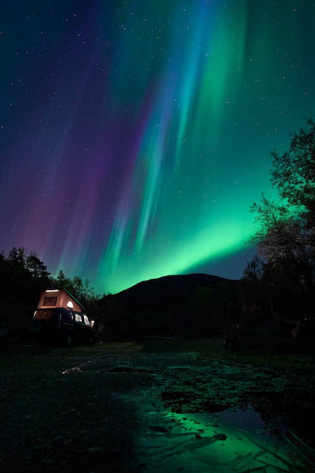 Northern lights arching over a Norwegian fjord.